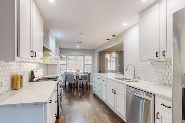 kitchen featuring appliances with stainless steel finishes, dark wood-type flooring, sink, decorative light fixtures, and white cabinetry