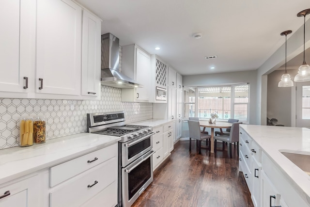 kitchen with white cabinetry, wall chimney exhaust hood, dark hardwood / wood-style floors, pendant lighting, and range with two ovens