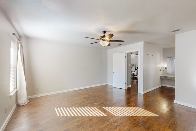 spare room featuring dark wood-type flooring, ceiling fan, and a healthy amount of sunlight