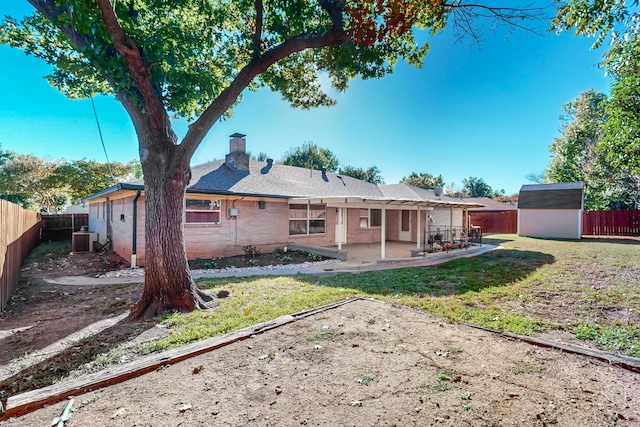 rear view of house with a lawn, a patio area, central AC unit, and a storage unit