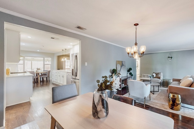 dining area featuring crown molding, an inviting chandelier, and hardwood / wood-style flooring