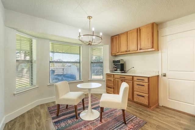 kitchen featuring a textured ceiling, decorative light fixtures, light hardwood / wood-style floors, and a notable chandelier