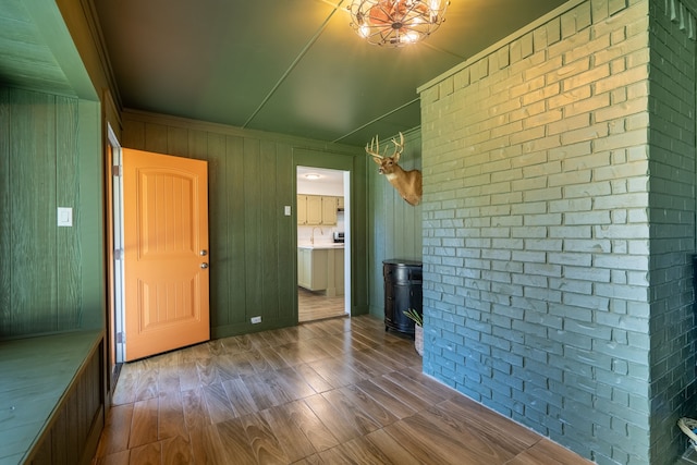 interior space with wood-type flooring, wood walls, and brick wall