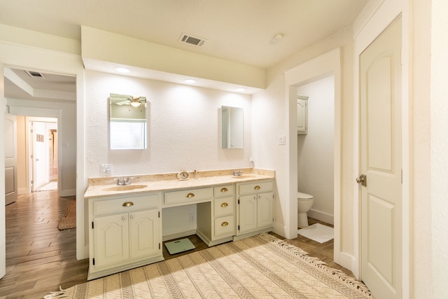 bathroom featuring wood-type flooring, vanity, toilet, and ceiling fan