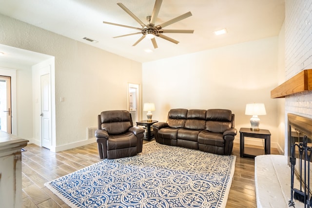 living room featuring a fireplace, light hardwood / wood-style flooring, and ceiling fan