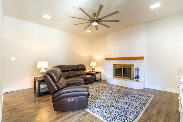 living room featuring ceiling fan, wood-type flooring, and a brick fireplace