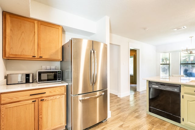 kitchen with an inviting chandelier, hanging light fixtures, light hardwood / wood-style flooring, black dishwasher, and stainless steel refrigerator