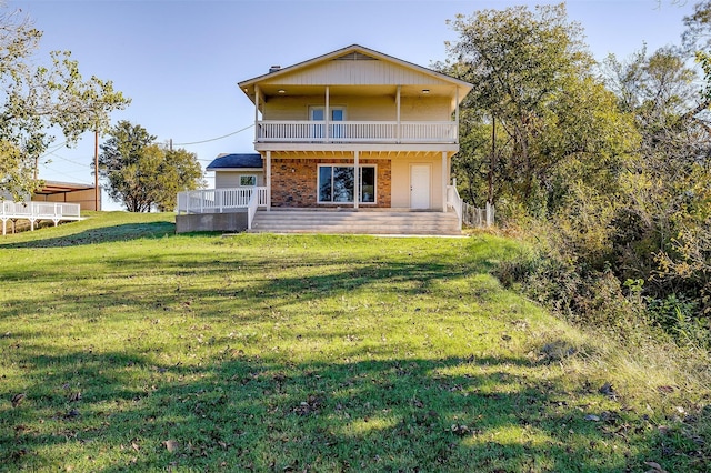 rear view of house featuring a patio, a balcony, and a lawn