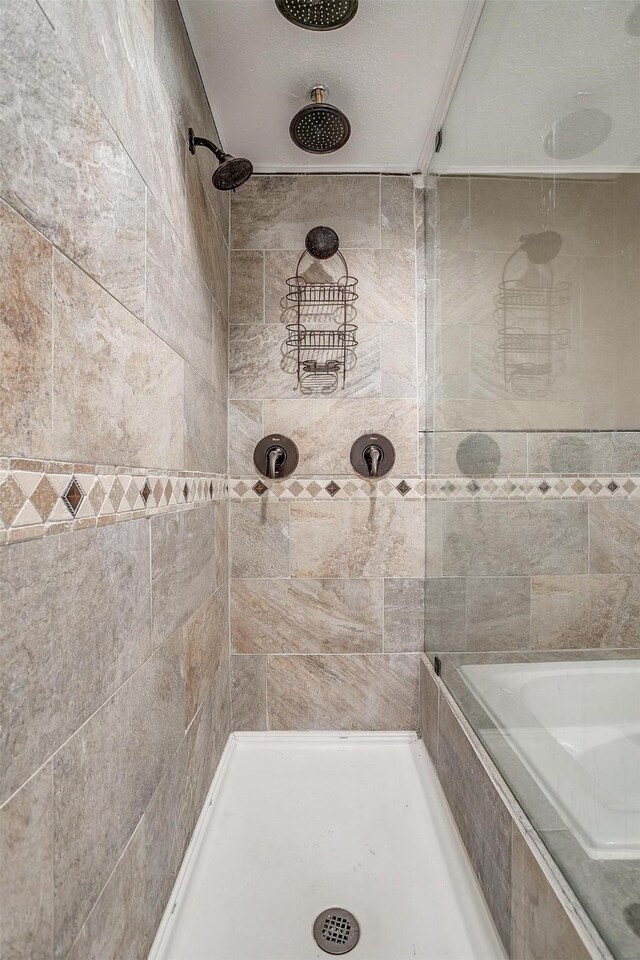 bathroom with a tile shower and a textured ceiling