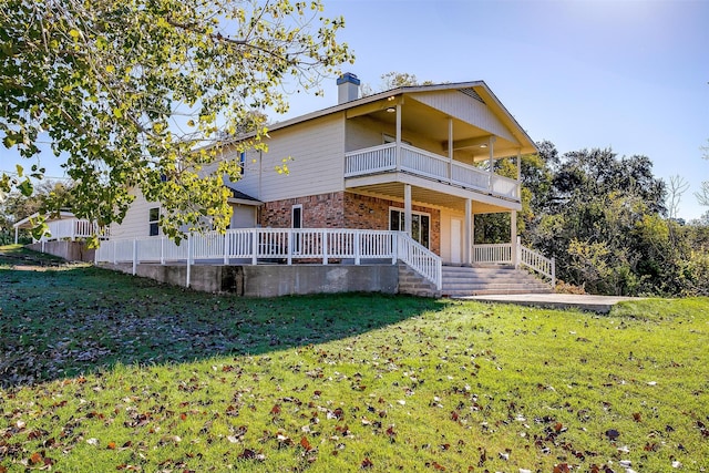 back of house featuring covered porch, a yard, and a balcony