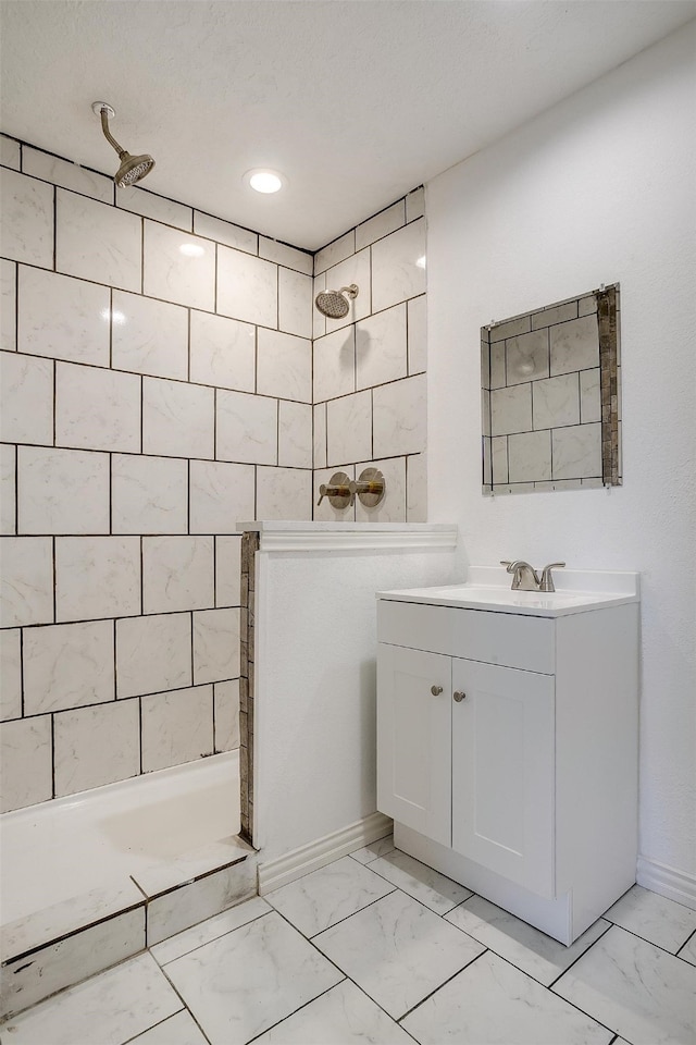 bathroom featuring tiled shower, a textured ceiling, and vanity