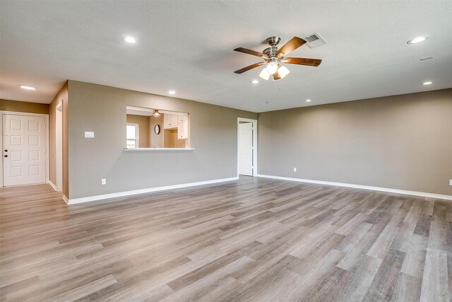 unfurnished living room with a textured ceiling, light hardwood / wood-style flooring, and ceiling fan