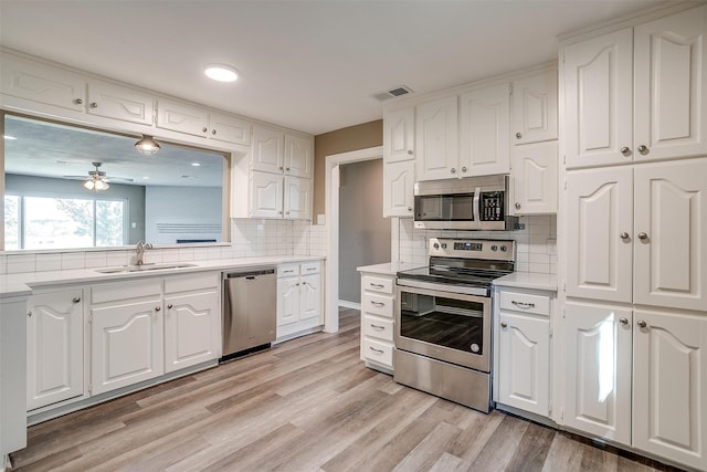 kitchen featuring appliances with stainless steel finishes, light wood-type flooring, white cabinetry, and sink