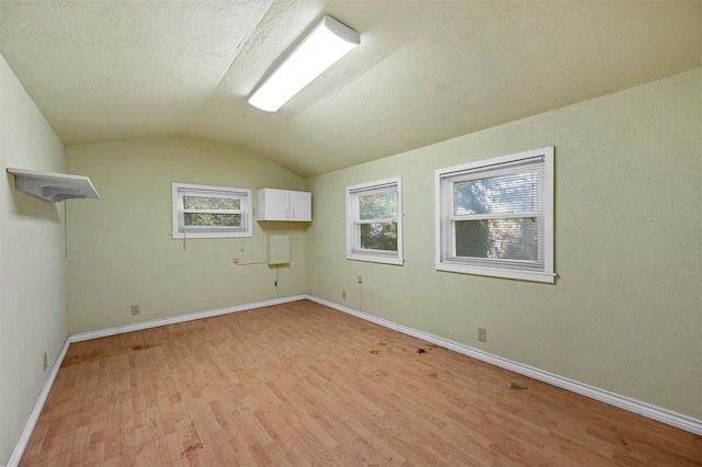 bonus room with light wood-type flooring and vaulted ceiling