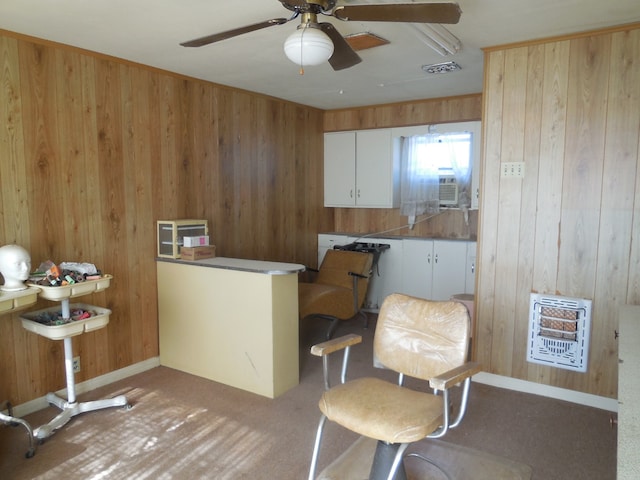 living area with heating unit, wood walls, carpet, and ceiling fan