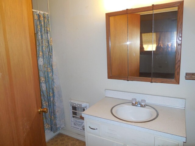 bathroom featuring a shower with shower curtain, vanity, and heating unit