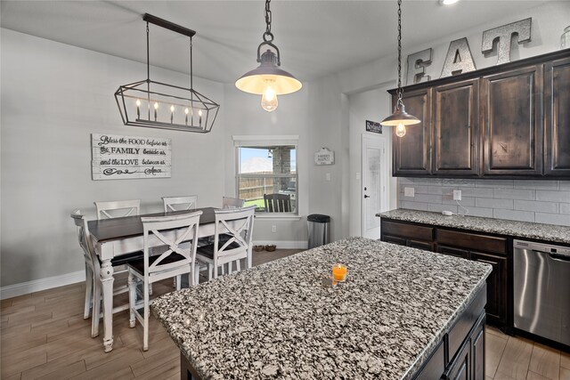 kitchen featuring tasteful backsplash, pendant lighting, light hardwood / wood-style flooring, dishwasher, and a kitchen island