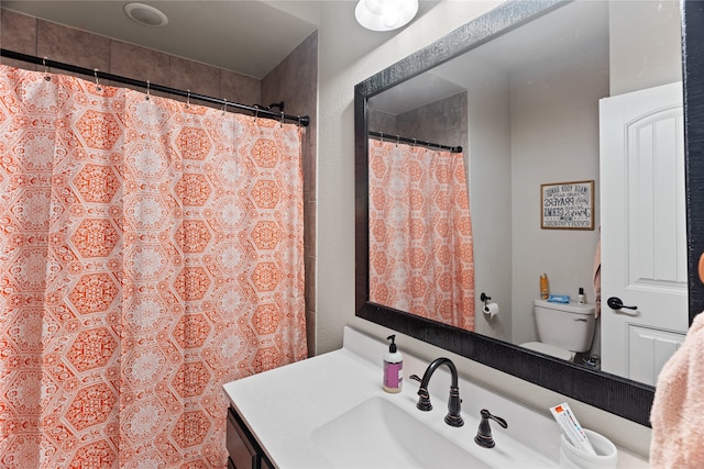 bathroom with curtained shower, vanity, and toilet