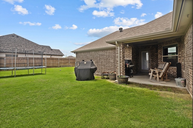 rear view of house featuring a trampoline, a patio, and a yard