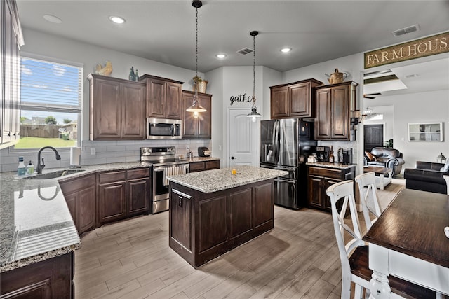 kitchen with sink, decorative light fixtures, decorative backsplash, a kitchen island, and appliances with stainless steel finishes