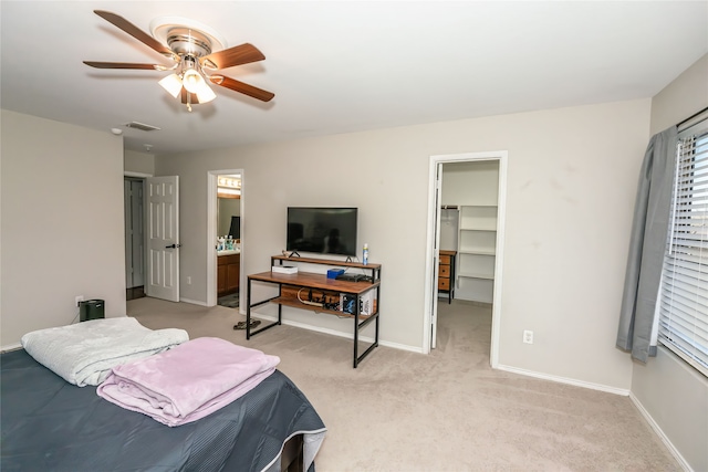 bedroom with a walk in closet, light colored carpet, ceiling fan, connected bathroom, and a closet