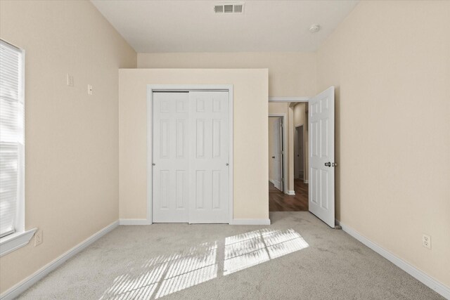 unfurnished bedroom featuring light carpet and a closet