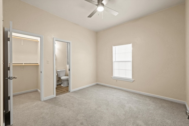 unfurnished bedroom featuring ceiling fan, a spacious closet, connected bathroom, light colored carpet, and a closet