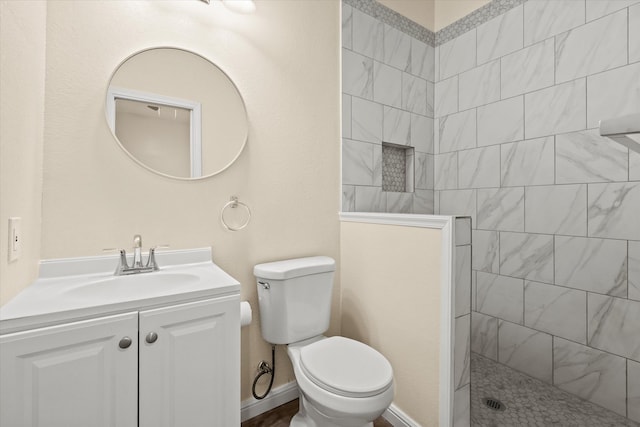 bathroom featuring a tile shower, vanity, and toilet