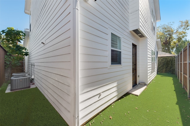 view of property exterior with central AC unit and a lawn