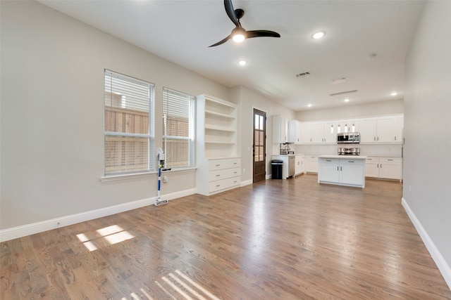 unfurnished living room with ceiling fan, a healthy amount of sunlight, and light hardwood / wood-style flooring