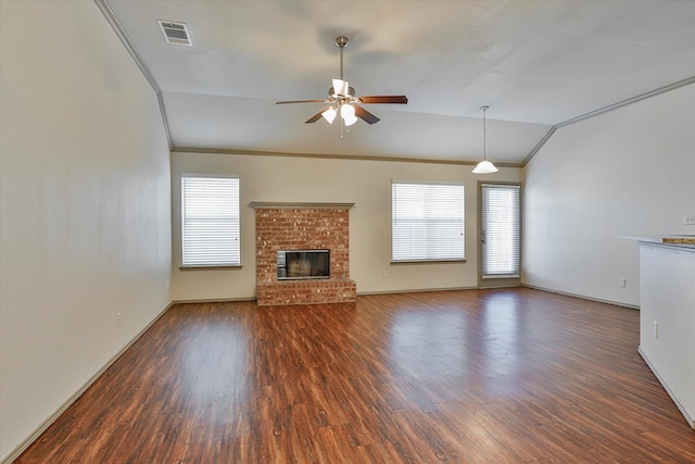 unfurnished living room featuring ceiling fan, a brick fireplace, dark hardwood / wood-style floors, crown molding, and vaulted ceiling