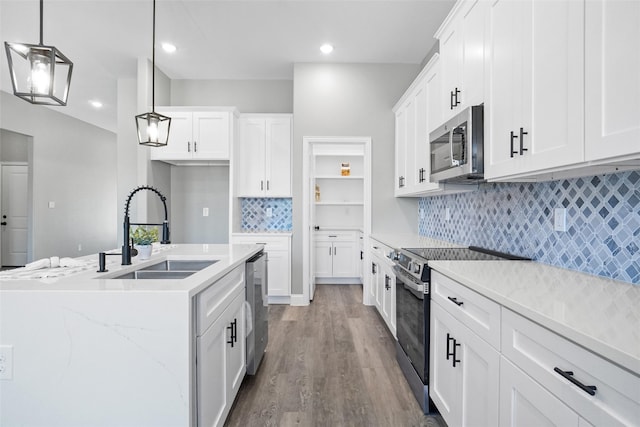 kitchen featuring white cabinetry, sink, stainless steel appliances, light hardwood / wood-style floors, and decorative light fixtures