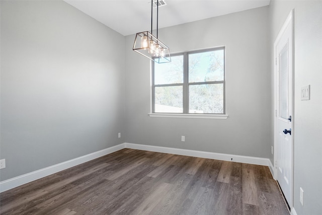 empty room with a chandelier and dark wood-type flooring