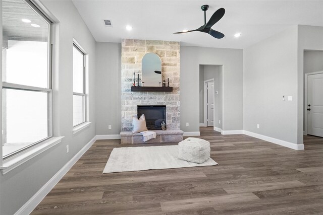 living room with dark hardwood / wood-style floors, ceiling fan, a stone fireplace, and a wealth of natural light