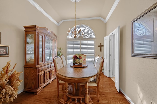 dining space featuring wood-type flooring, lofted ceiling, and ornamental molding