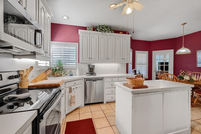 kitchen with stainless steel appliances, a center island, white cabinetry, hanging light fixtures, and light tile patterned flooring