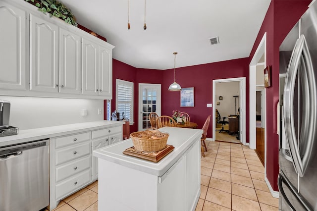 kitchen with a kitchen island, white cabinets, light tile patterned floors, and appliances with stainless steel finishes