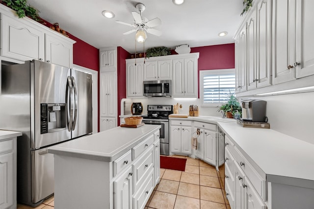 kitchen featuring white cabinets, stainless steel appliances, a kitchen island, and light tile patterned flooring