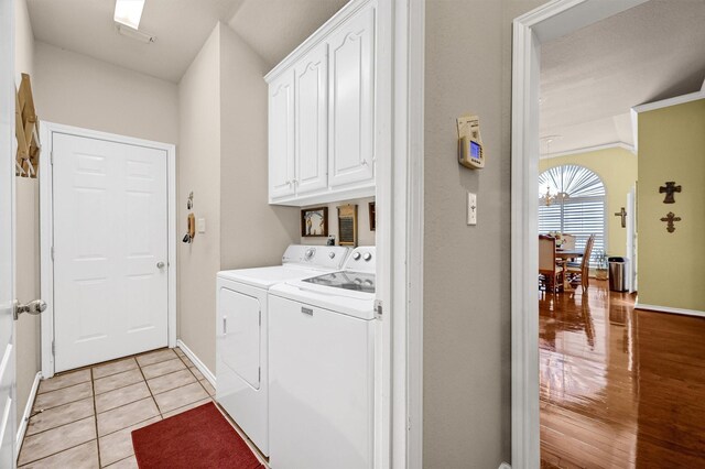 clothes washing area with washer and dryer, cabinets, and light hardwood / wood-style flooring