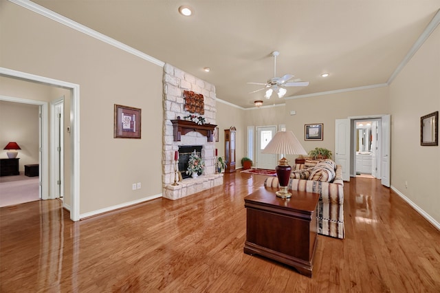 living room with crown molding, a fireplace, ceiling fan, and wood-type flooring