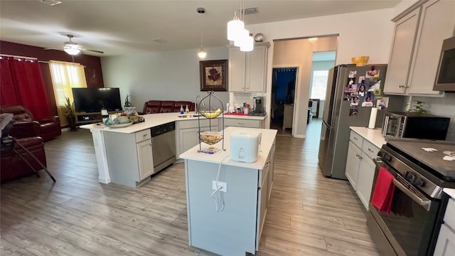 kitchen featuring appliances with stainless steel finishes, a kitchen island, plenty of natural light, and gray cabinetry