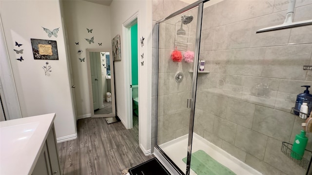 bathroom with walk in shower, hardwood / wood-style floors, vanity, and toilet