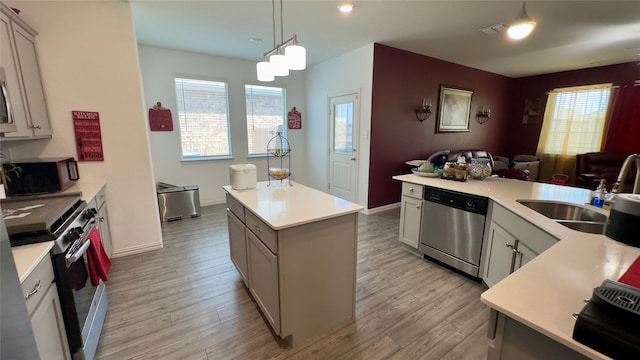 kitchen featuring a center island, a healthy amount of sunlight, decorative light fixtures, and appliances with stainless steel finishes