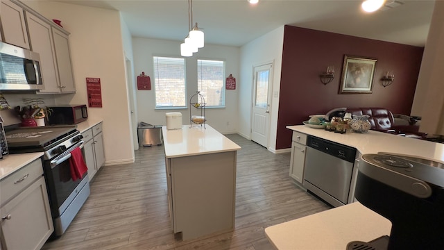 kitchen featuring pendant lighting, a center island with sink, light hardwood / wood-style flooring, and appliances with stainless steel finishes