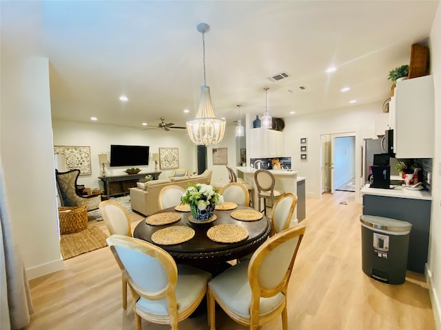 dining space featuring light hardwood / wood-style flooring and ceiling fan with notable chandelier