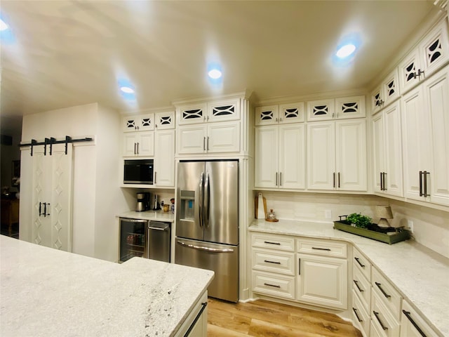 kitchen featuring stainless steel refrigerator with ice dispenser, black microwave, a barn door, light hardwood / wood-style floors, and wine cooler