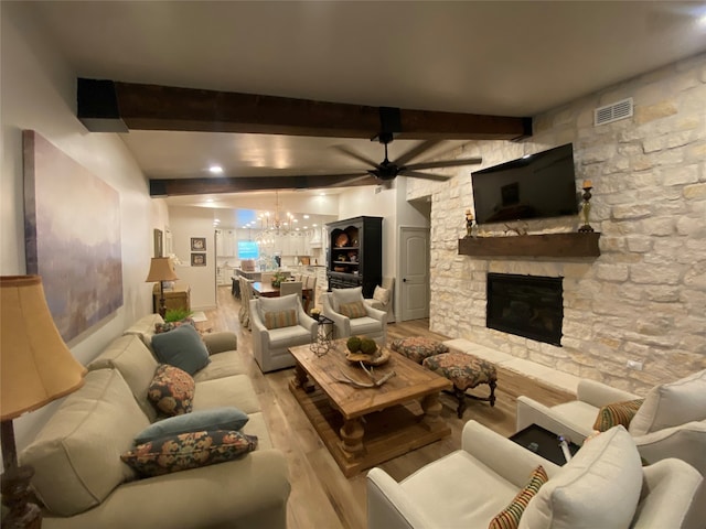 living room with beam ceiling, a fireplace, ceiling fan with notable chandelier, and light wood-type flooring