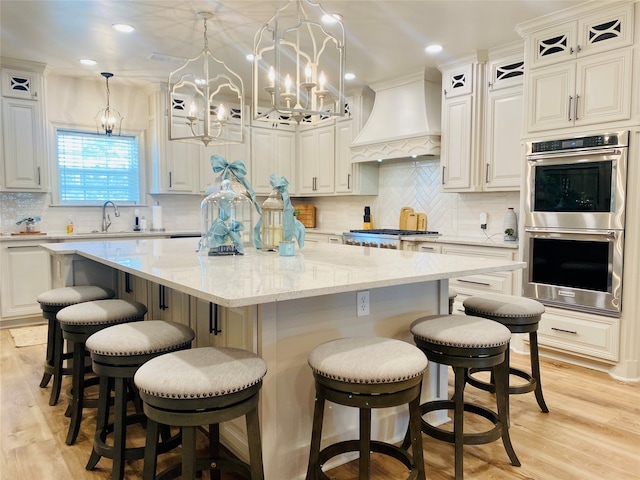 kitchen with premium range hood, white cabinets, a spacious island, and appliances with stainless steel finishes