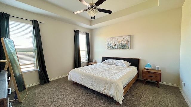 carpeted bedroom featuring a raised ceiling and ceiling fan