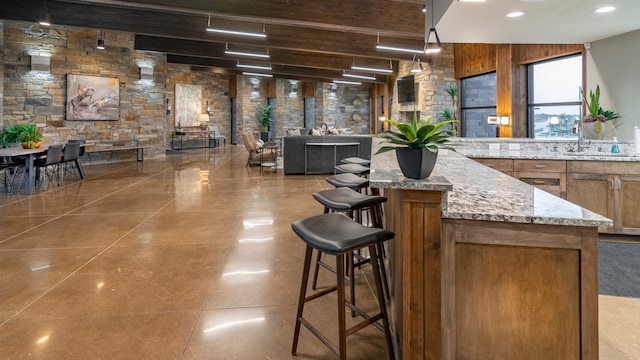 kitchen with backsplash, kitchen peninsula, light stone counters, white cabinetry, and stainless steel refrigerator